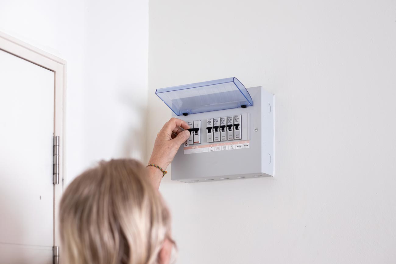 A man turns on a switch on an electrical panel in a room