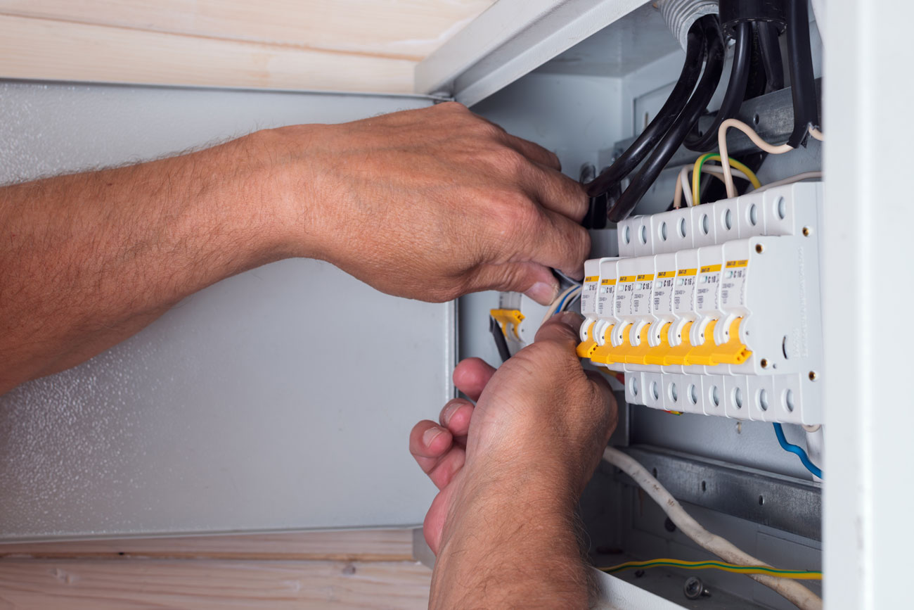 Electrician's hands skillfully connecting cables in an open distribution board