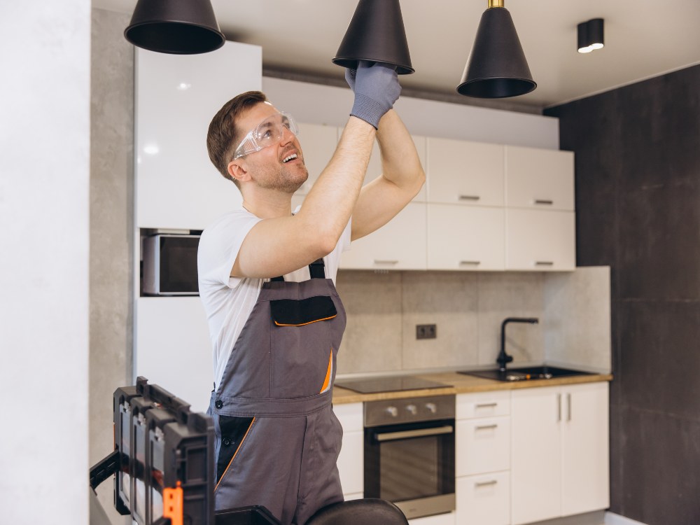 Electrician installing a modern pendant light fixture in a Grimes, IA home.