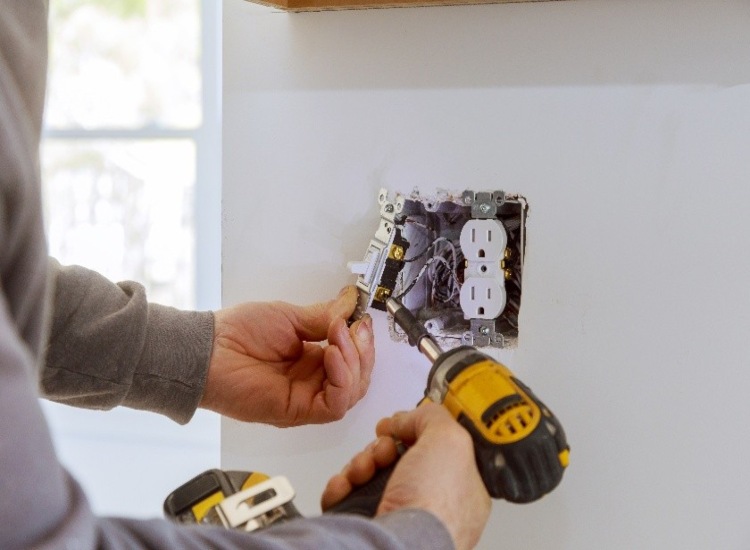 Electrician replacing worn light wall switches to improve safety in Grimes, IA