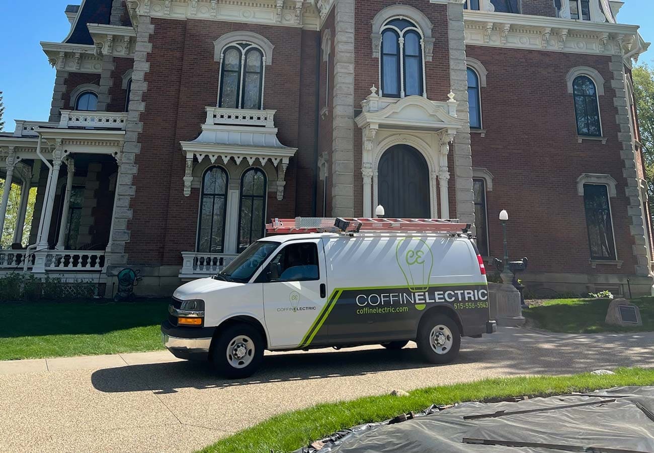 A white van from Coffin Electric parked in front of a large mansion in Grimes, IA.