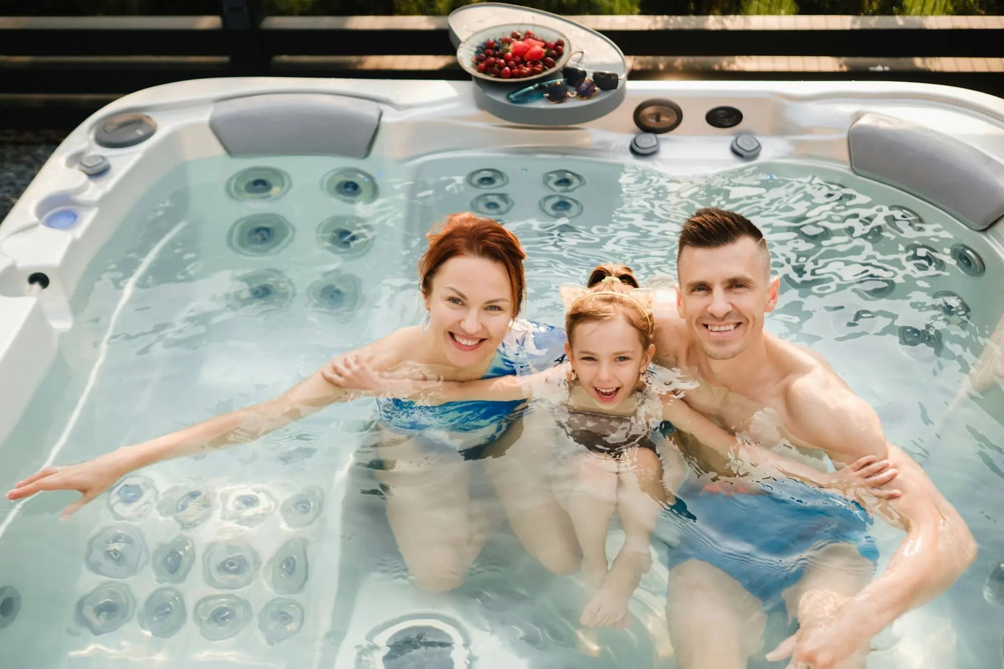 A happy family enjoys bonding time in a backyard hot tub, smiling & relaxing together in Grimes, IA.