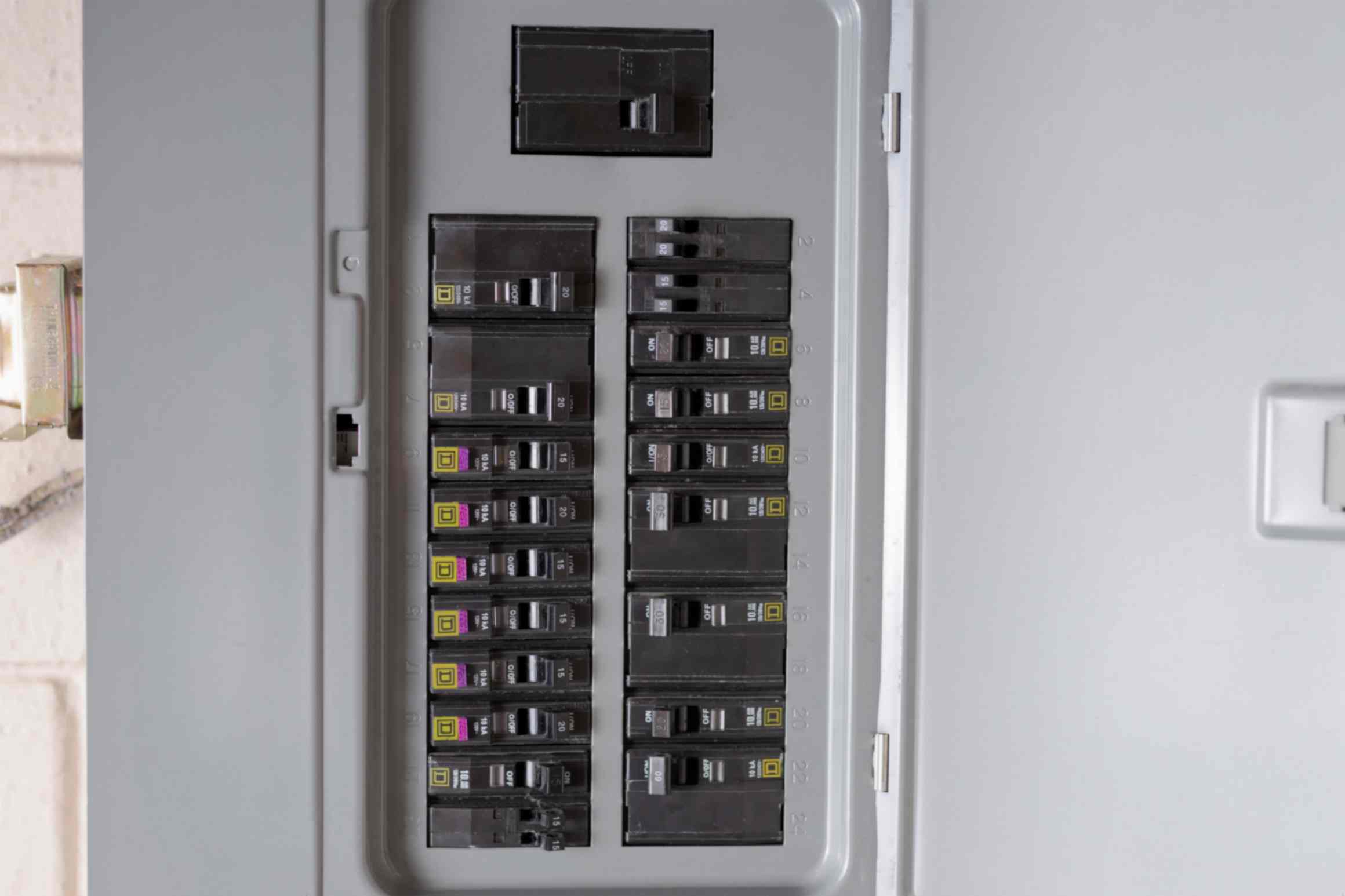 A woman inspects a fuse box in a room, ensuring electrical safety and functionality in Grimes, IA.