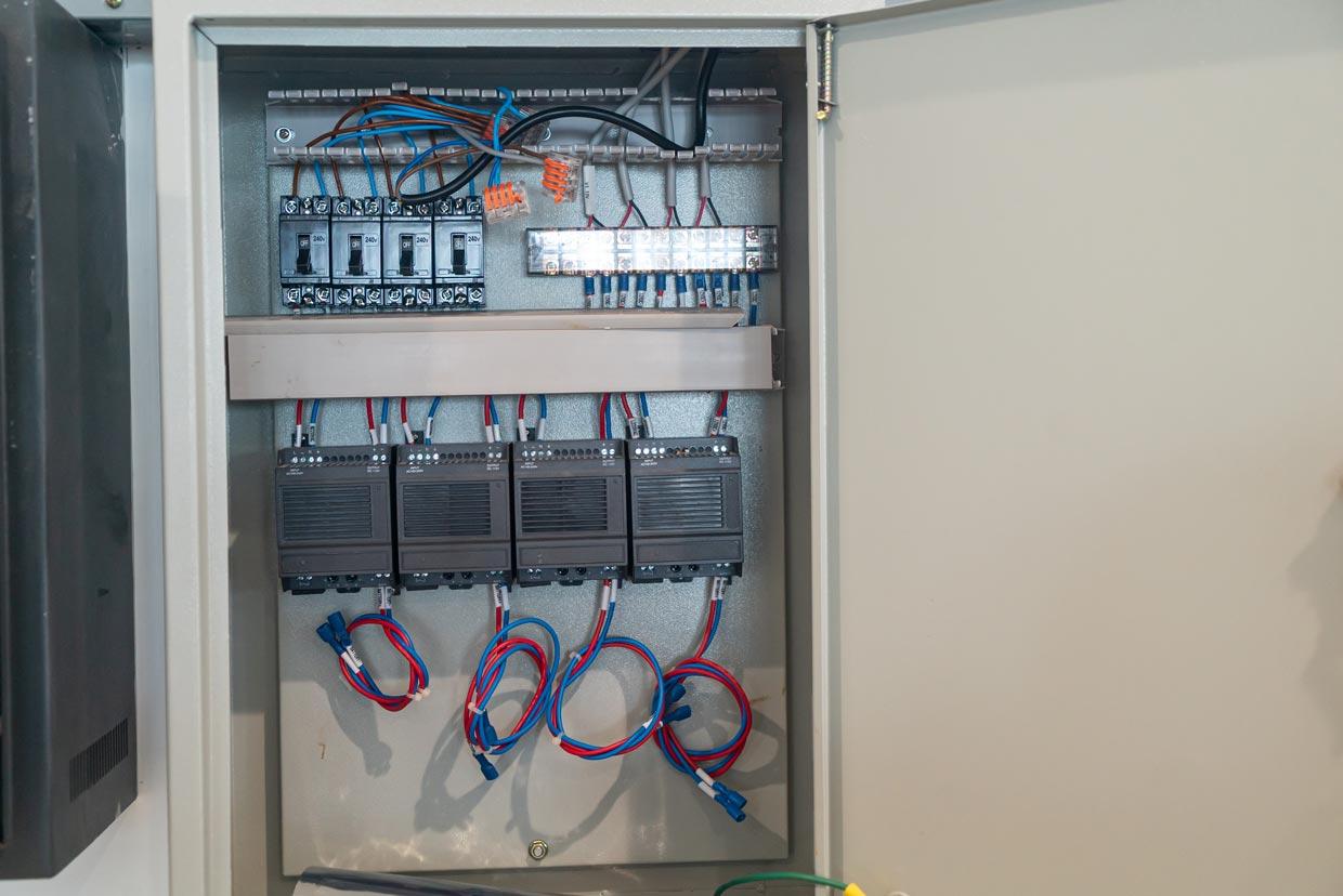 A surge protector cabinet with visible wires and a switch, located in Grimes, IA.